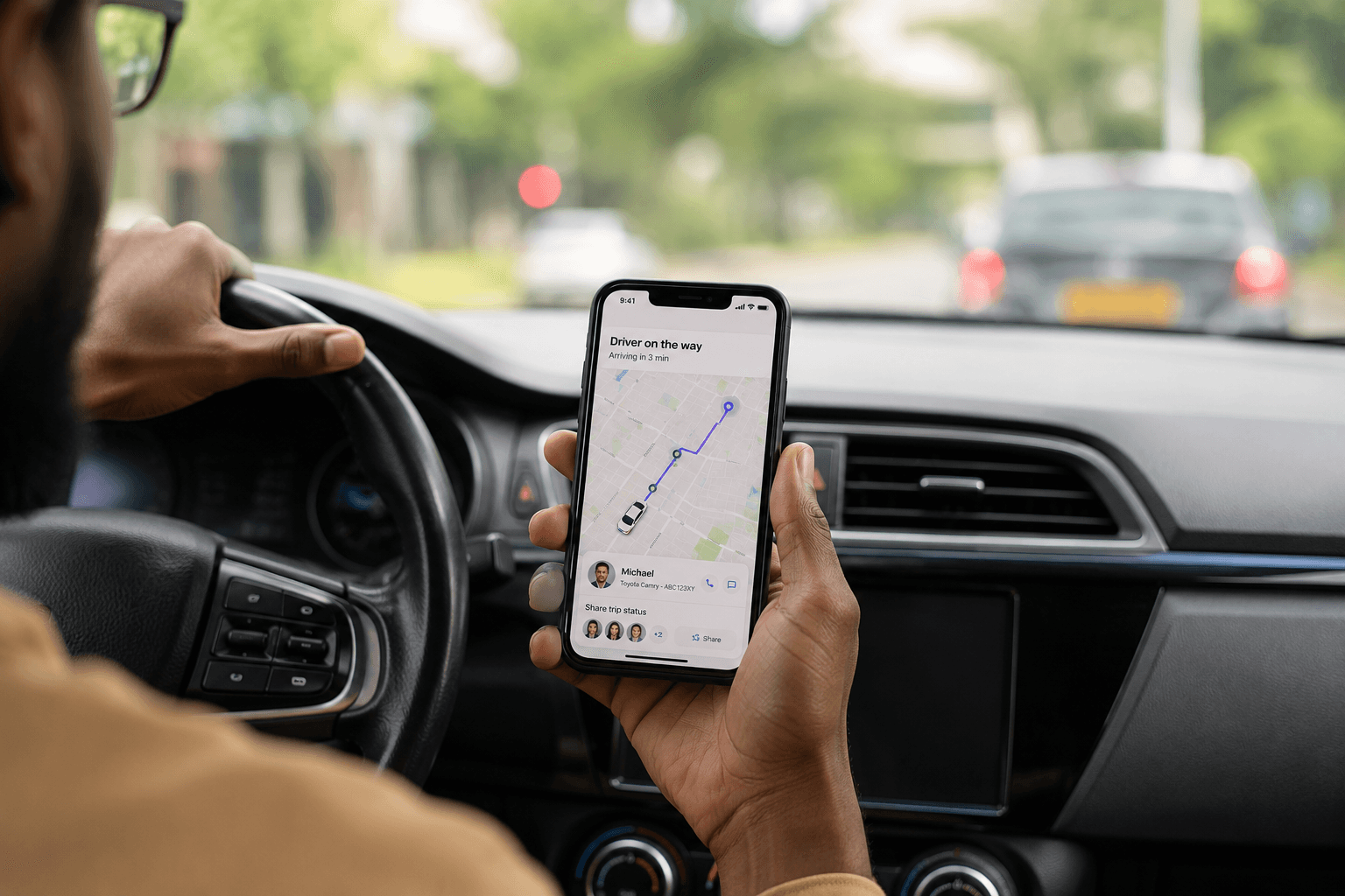 A driver holding a phone showing live ride tracking